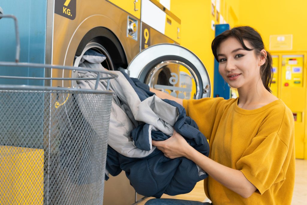 Asian people using qualified coin operated laundry machine in the public room to wash their cloths. Concept of a self service commercial laundry and drying machine in a public room.